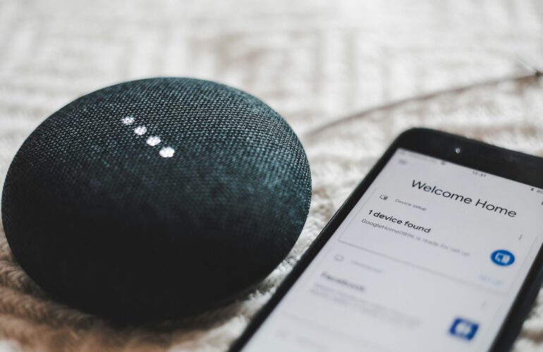 Turned-on charcoal Google Home Mini and smartphone photo