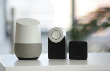 white and gray Google smart speaker and wo black speakers