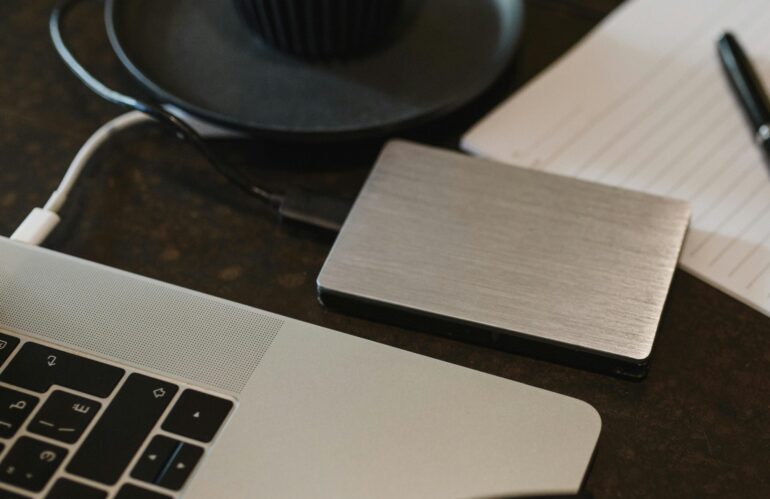 Free Closeup of an external hard drive connected to a laptop with a USB cable on a desk. Stock Photo